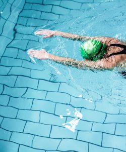 Fit,Woman,Swimming,With,Swimming,Hat,In,Swimming,Pool